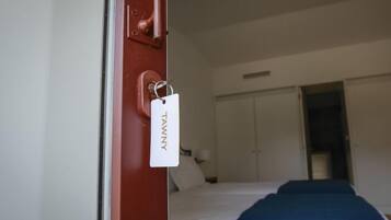 Una camera d'albergo con un letto, un armadio e una porta con un cartellino.