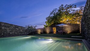 A swimming pool with stone walls and a patio area with outdoor furniture. - Morgadio da Calçada (Sabrosa)
