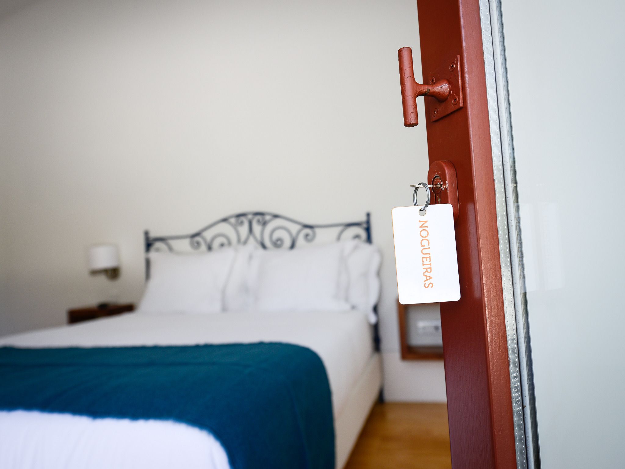 Une chambre d’hôtel avec un lit, une table de chevet et une lampe fixée au mur.