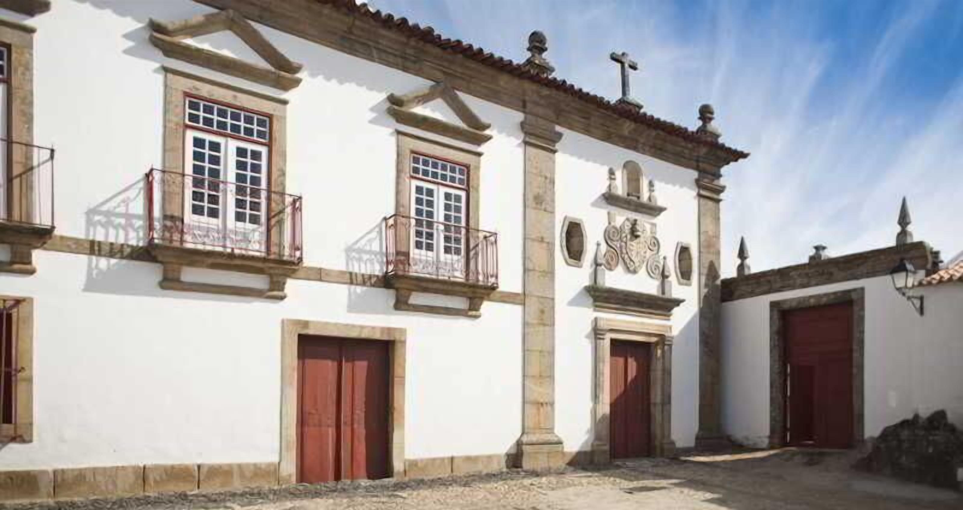 A building with a white facade, multiple windows, and red doors.