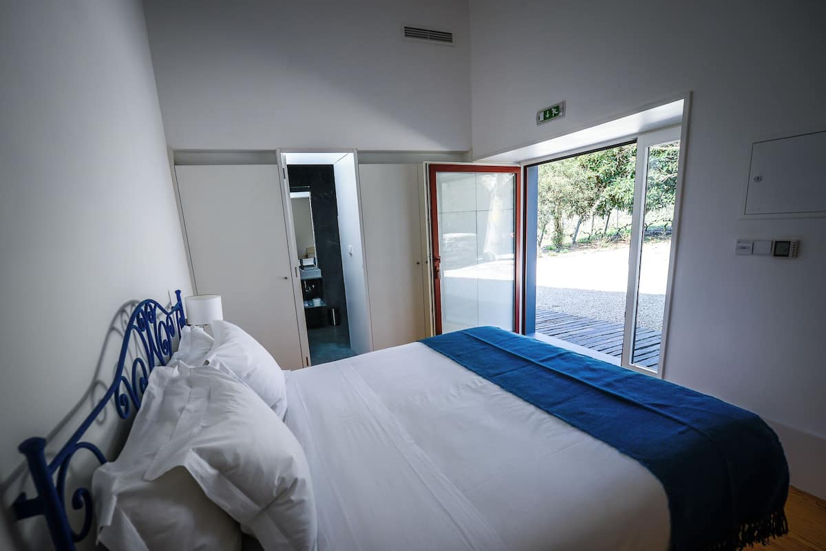 A bedroom with a bed, a wardrobe, and a door leading to an outdoor area.