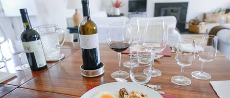 A dining table with a plate of food, wine glasses, and bottles.
