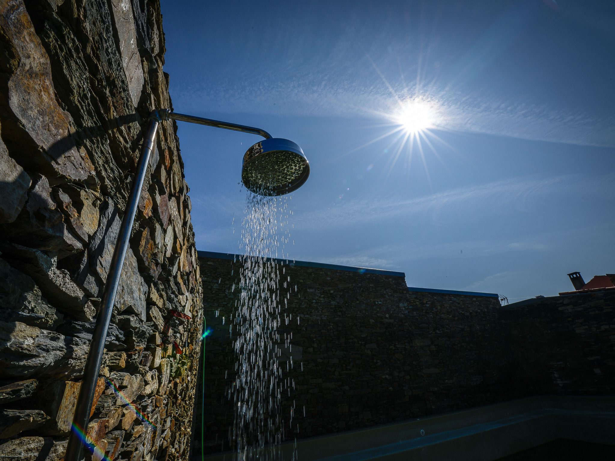 A stone wall with a metal structure and a clear blue sky.