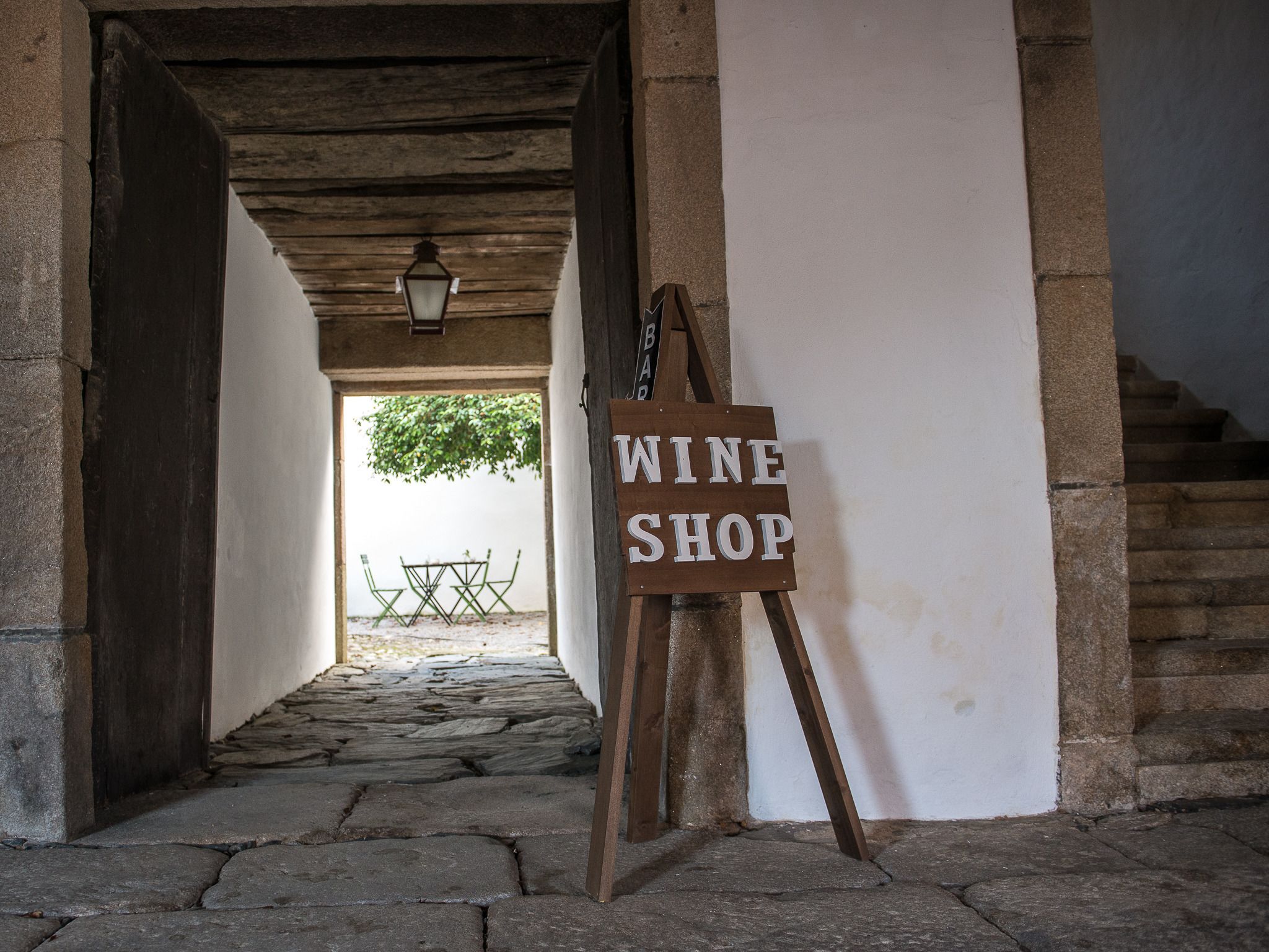 A stone-paved corridor leading to a wine shop sign.
