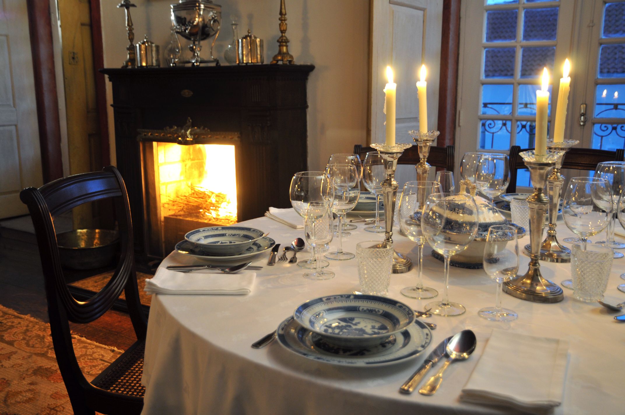 A dining table set for a meal with candles, plates, and cutlery.