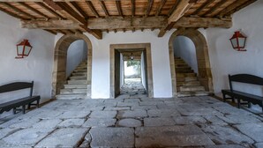 A stone-floored corridor with wooden beams and stone arches, leading to a staircase. - Morgadio da Calçada (Sabrosa)
