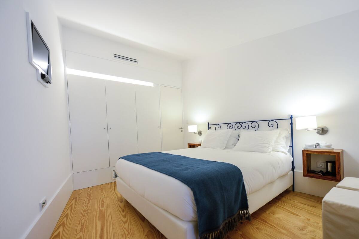 A bedroom with a bed, bedside tables, a wardrobe, and a nightstand.