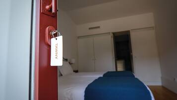 A hotel room with a bed, a wardrobe, and a door with a tag.
