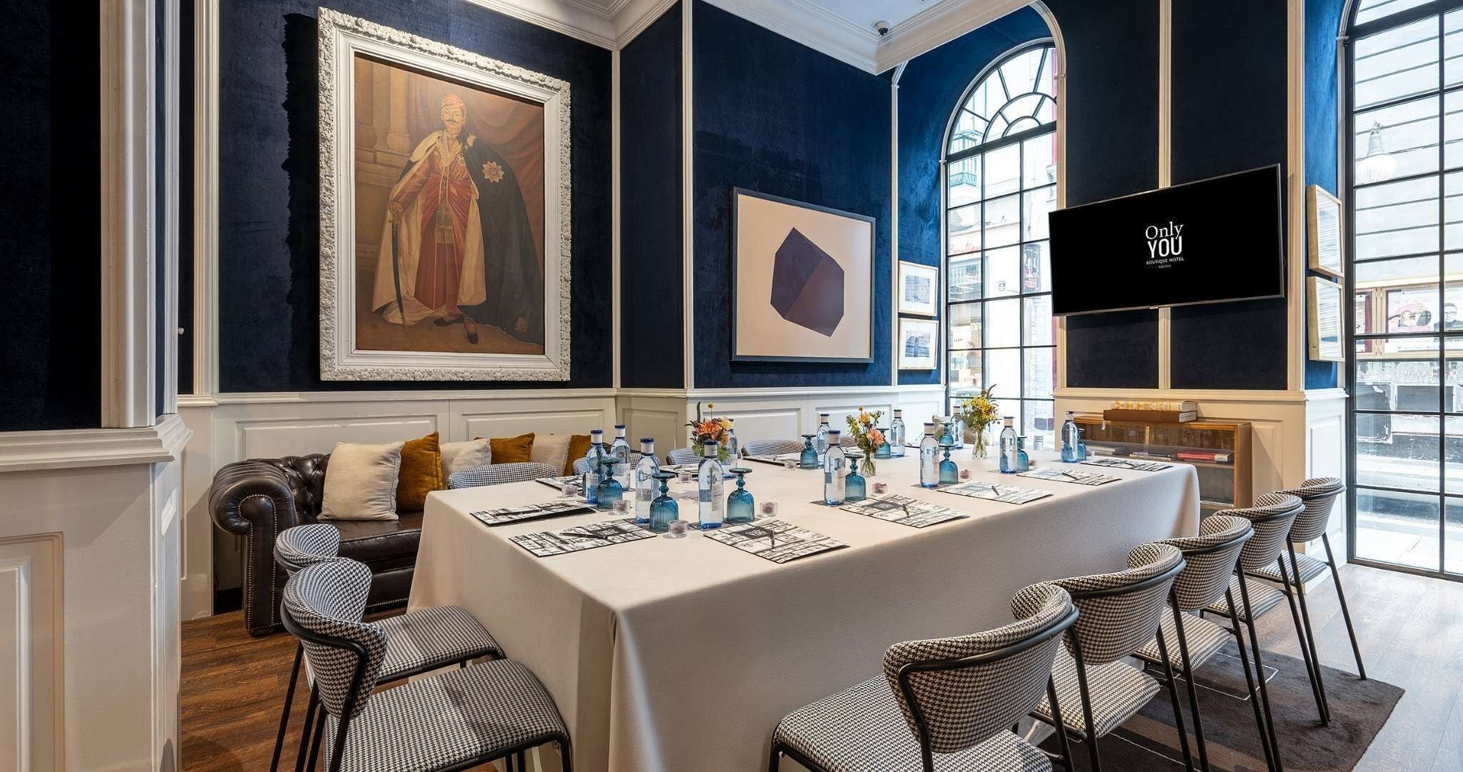 A conference room with a long table, chairs, a sofa, and a painting on the wall.