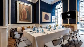 A conference room with a long table, chairs, a sofa, and a painting on the wall.