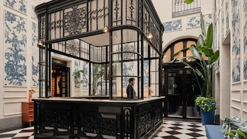 A black and white checkered floor, ornate black metal railings, and blue and white patterned walls.