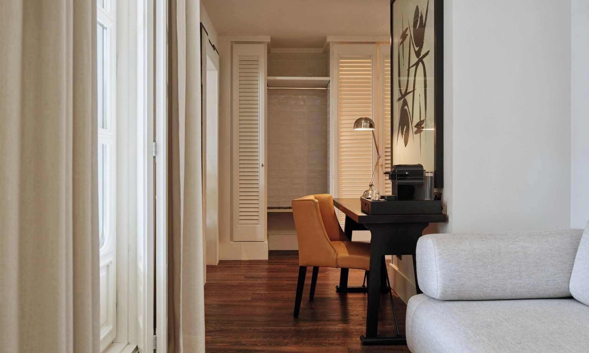 A hallway with a dining area, a sofa, and a printer on a table.