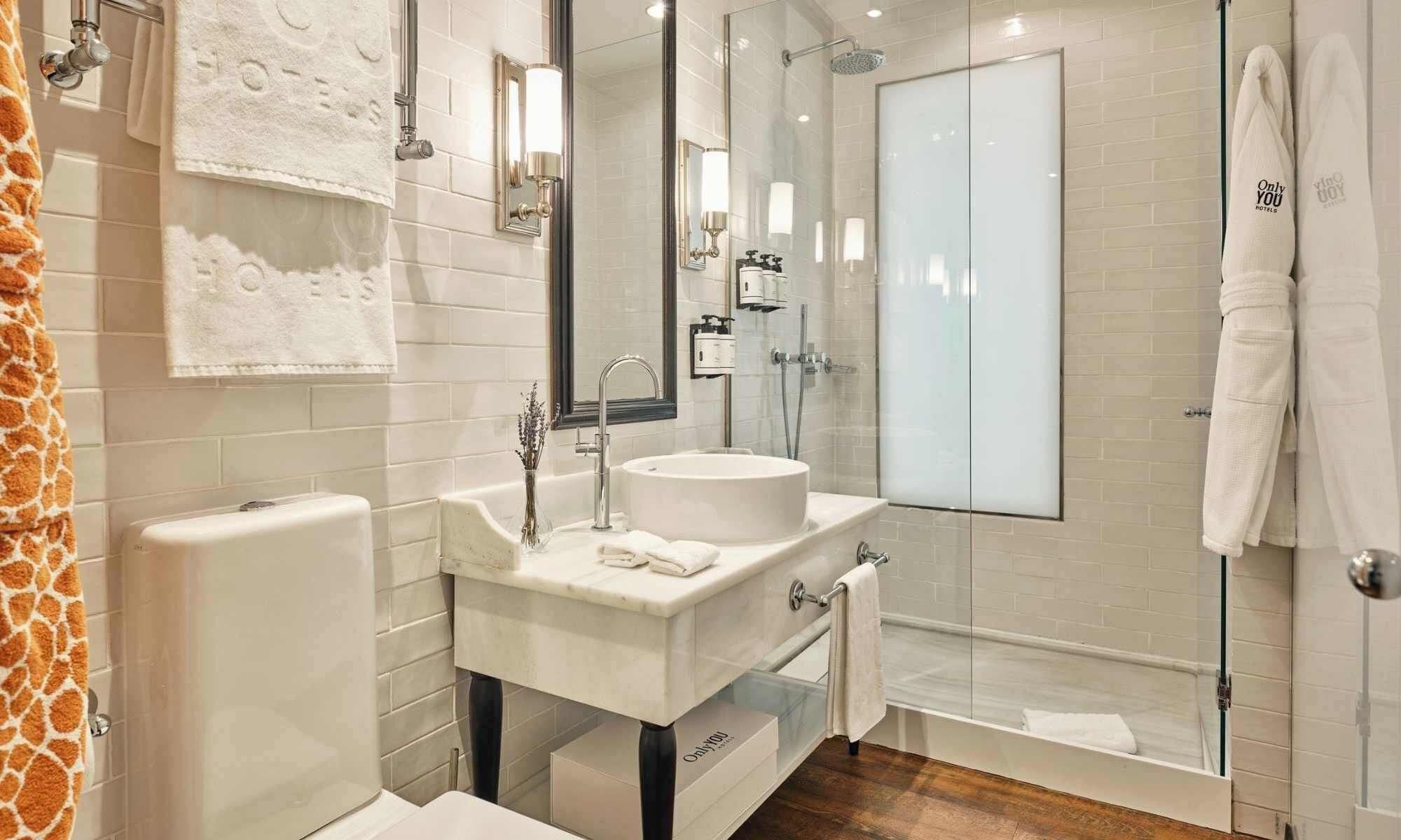 A modern bathroom with a white sink, mirror, and glass shower enclosure.