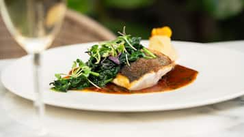 A plate of food with a glass of white wine on a table.