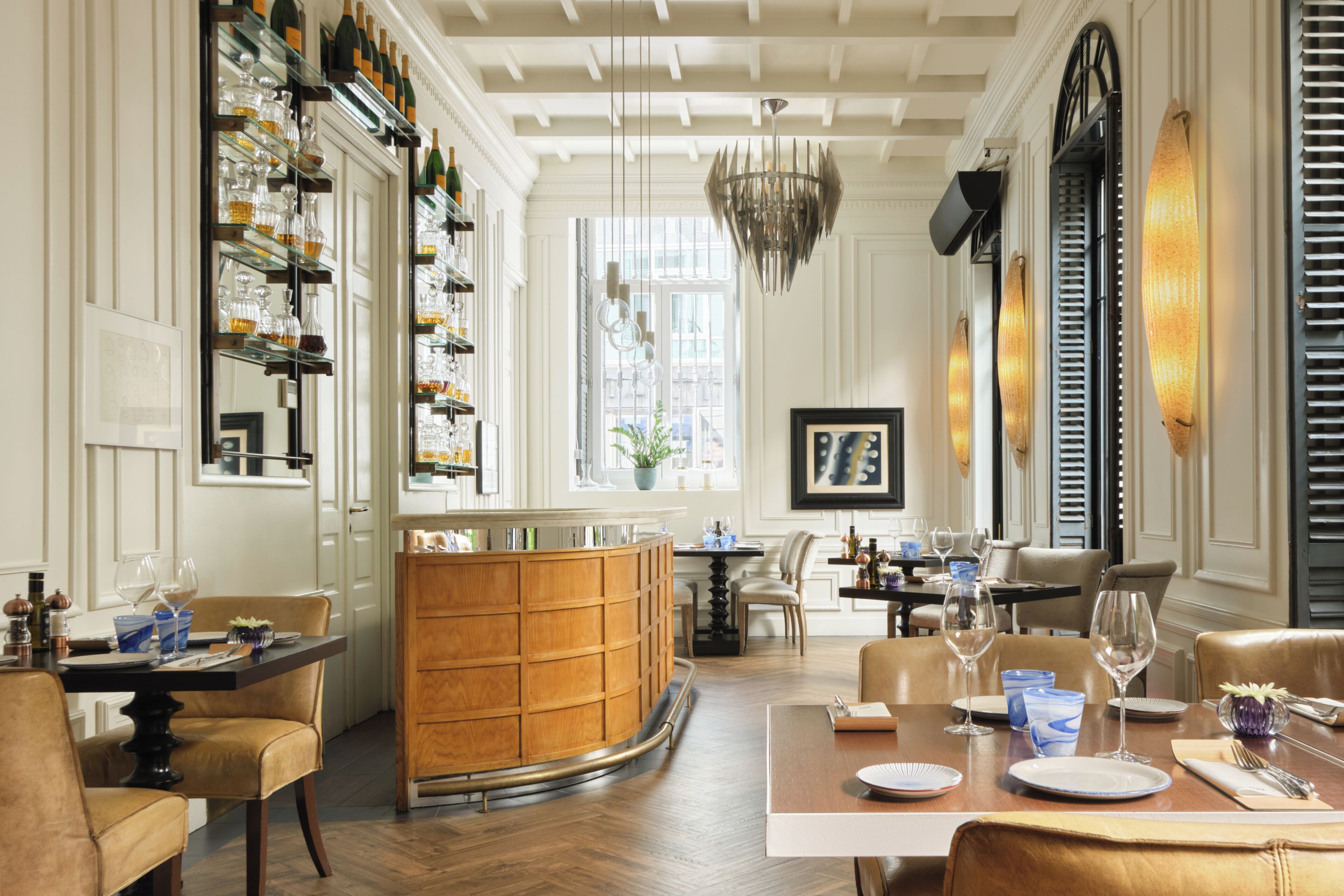 Un restaurante con zona de bar, muebles de madera y una lámpara de araña.