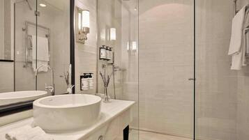 A modern bathroom with a glass-enclosed shower, a round sink, and a mirror.
