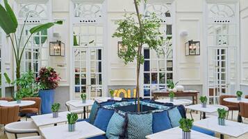 A hotel lobby with seating areas, tables, and potted plants.