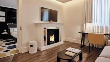 Una sala de estar moderna con chimenea, un televisor de pantalla plana encima, un escritorio con lámpara y un sofá.