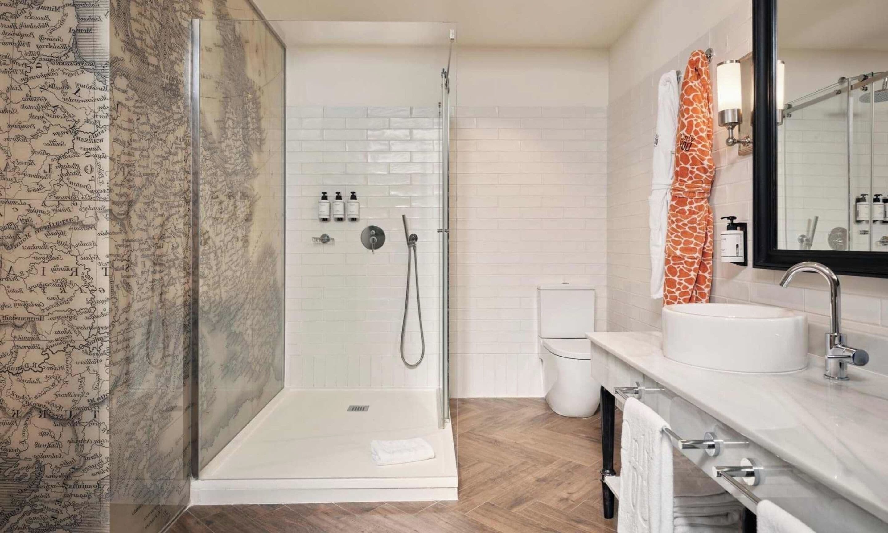 Une salle de bain moderne avec une douche à parois de verre, des carreaux blancs, un lavabo avec un miroir et un porte-serviettes.