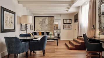 A modern living room with a dining area, featuring a large map on the wall, a sofa with cushions, and a coffee table.