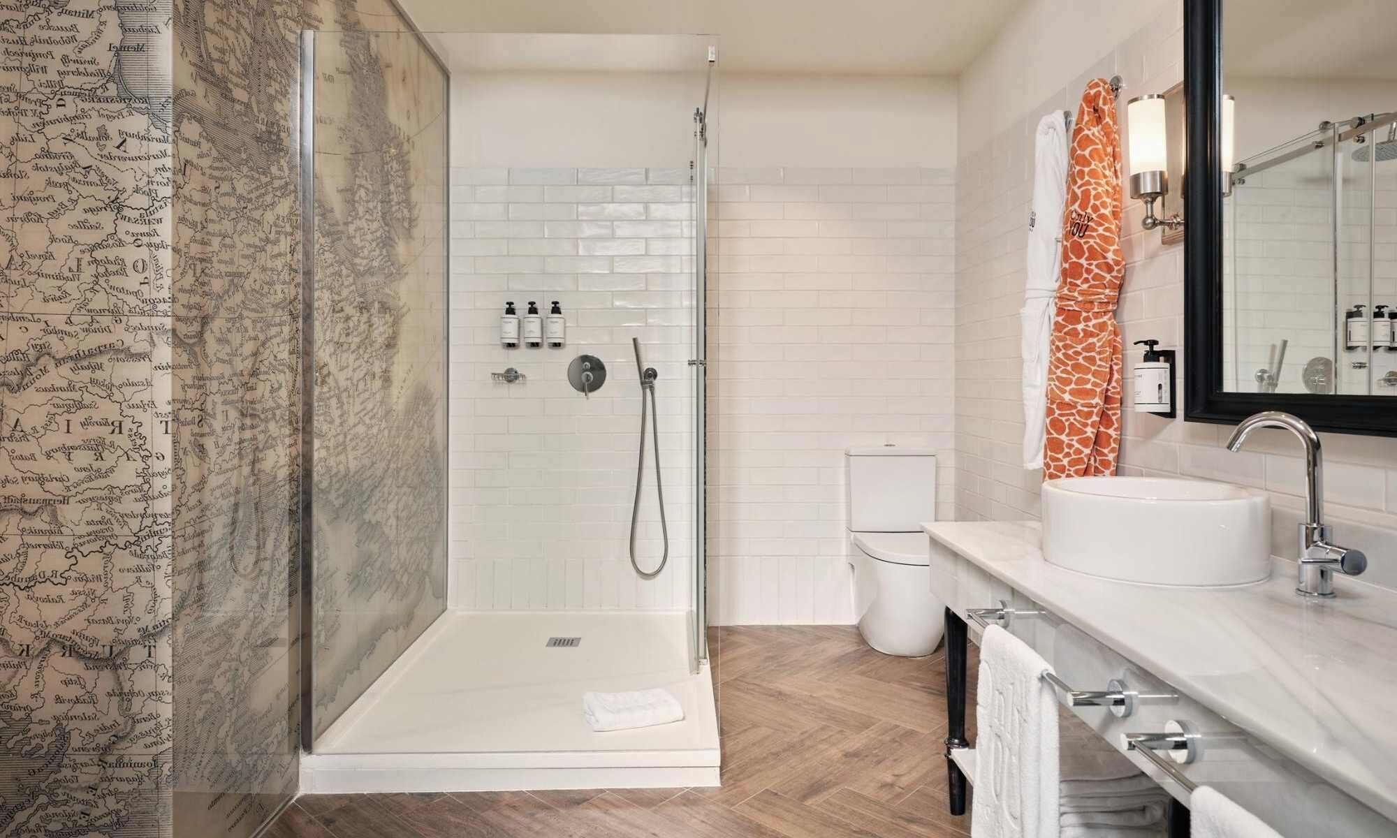 A modern bathroom with a glass shower enclosure, a white sink, and a mirror with a black frame.
