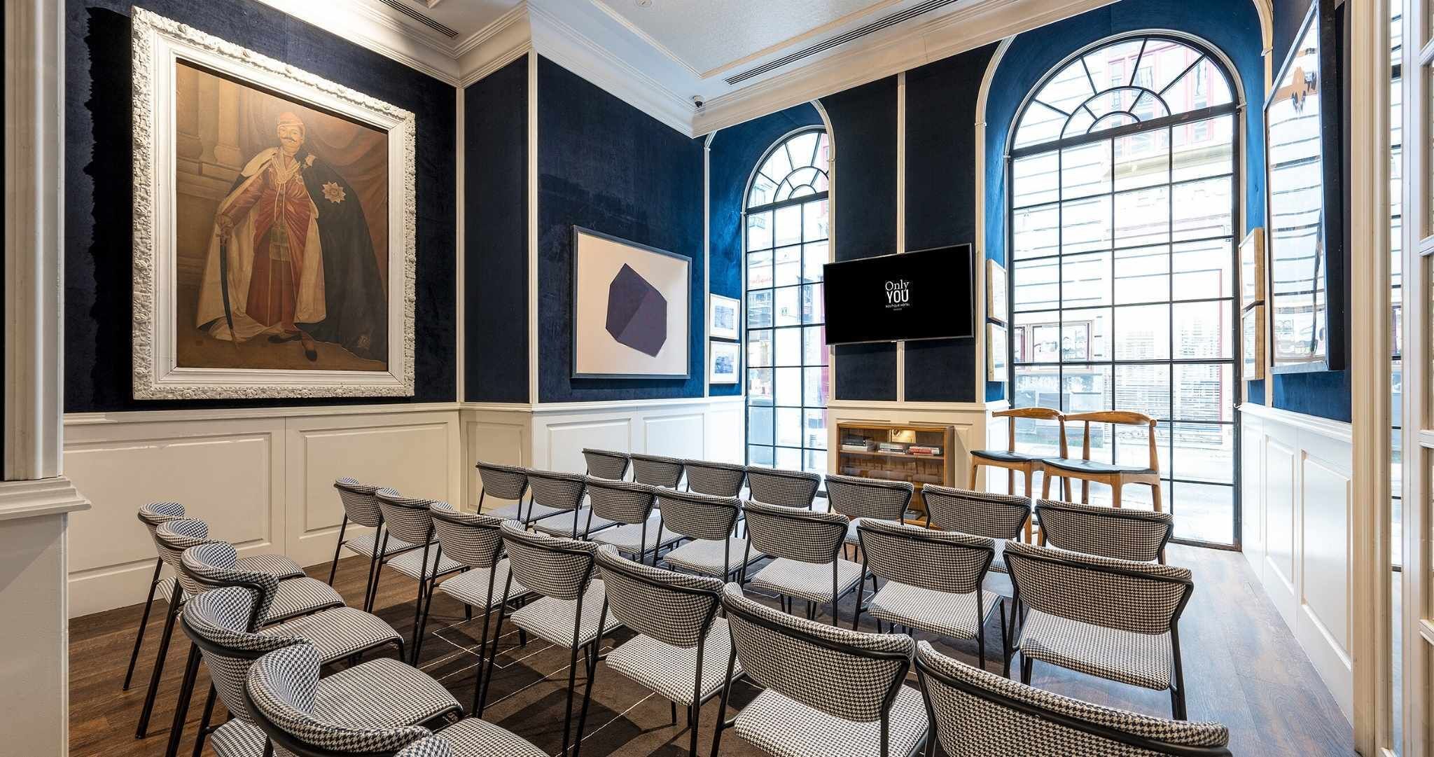Un salón de conferencias con un cuadro grande, una pantalla de televisión y vistas amplias a través de grandes ventanales.