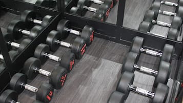 Una palestra con file di manubri neri e pareti con specchi.