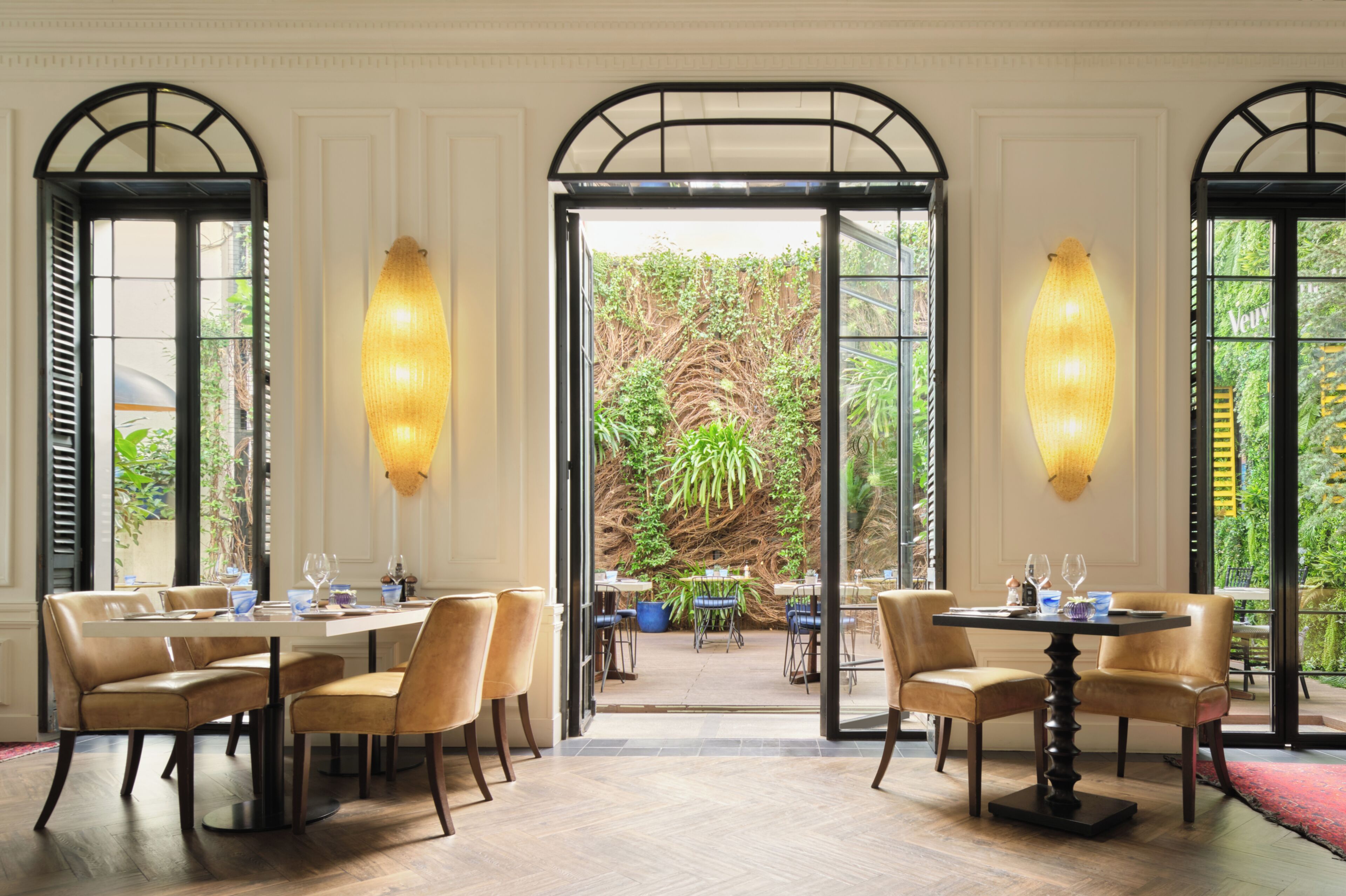 Un comedor con mesas y sillas, ventanas amplias y vista a la vegetación exterior.