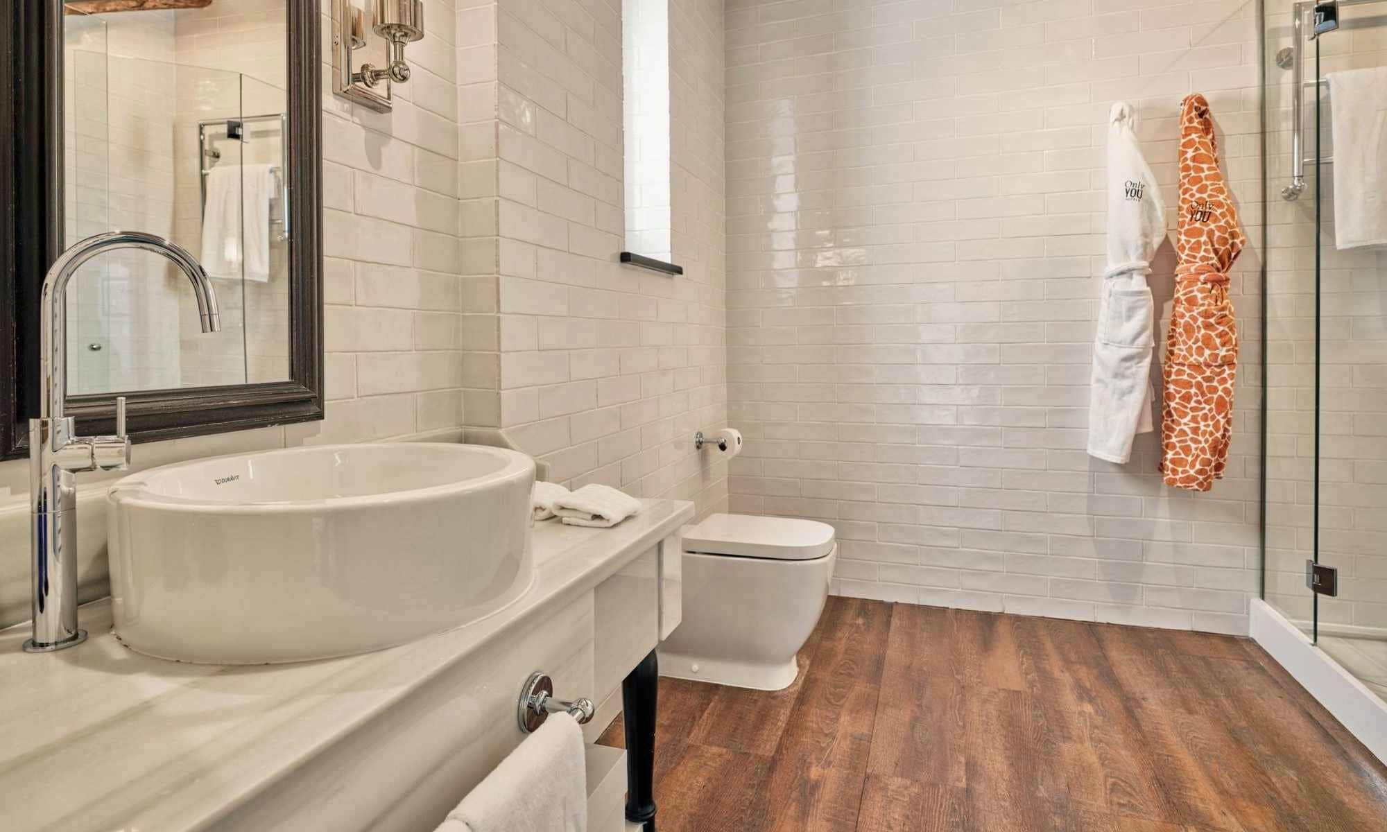 A bathroom with a large sink, toilet, and a glass shower enclosure.