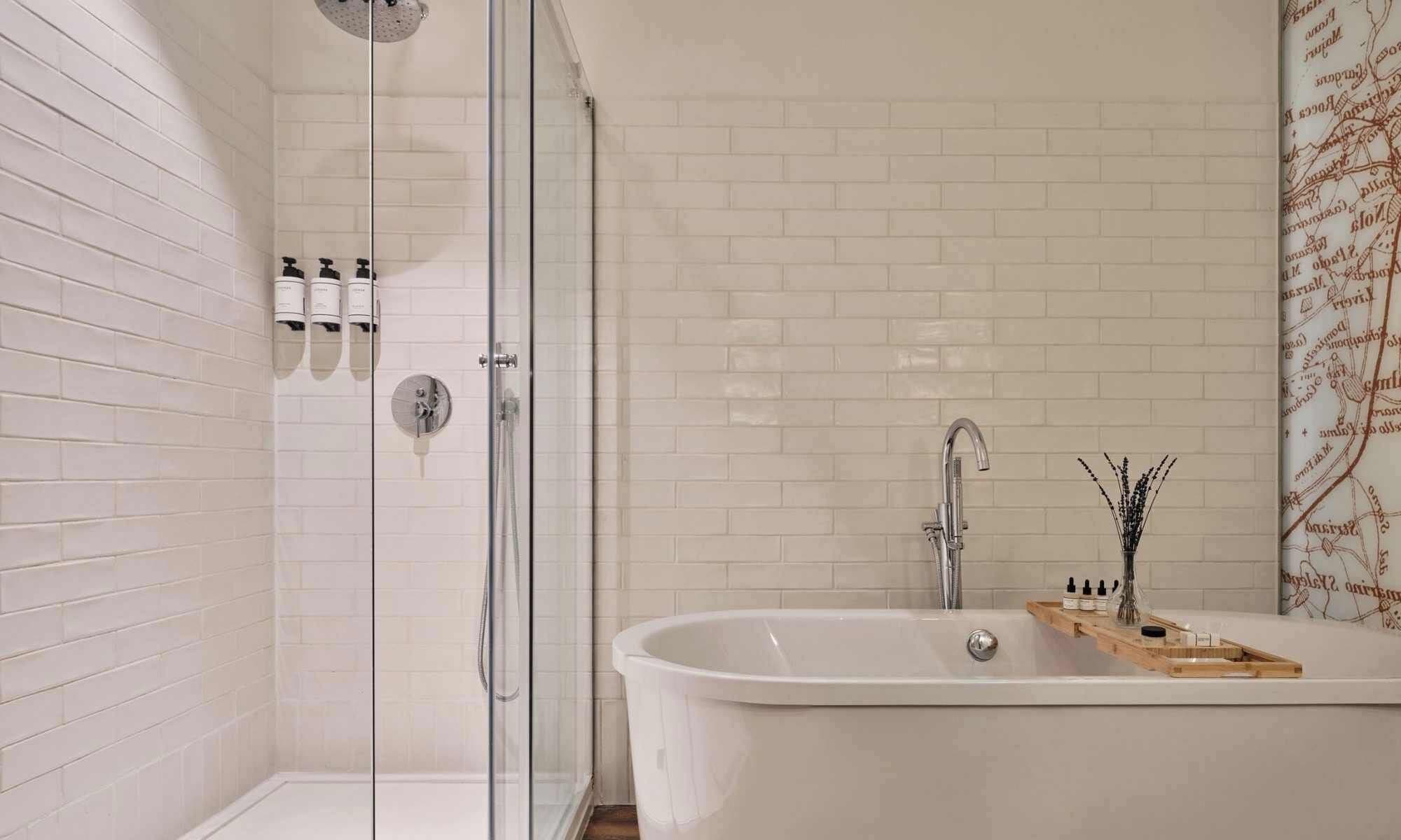 Un baño con cabina de ducha de vidrio, una bañera independiente y una pared de azulejos con un mapa decorativo.