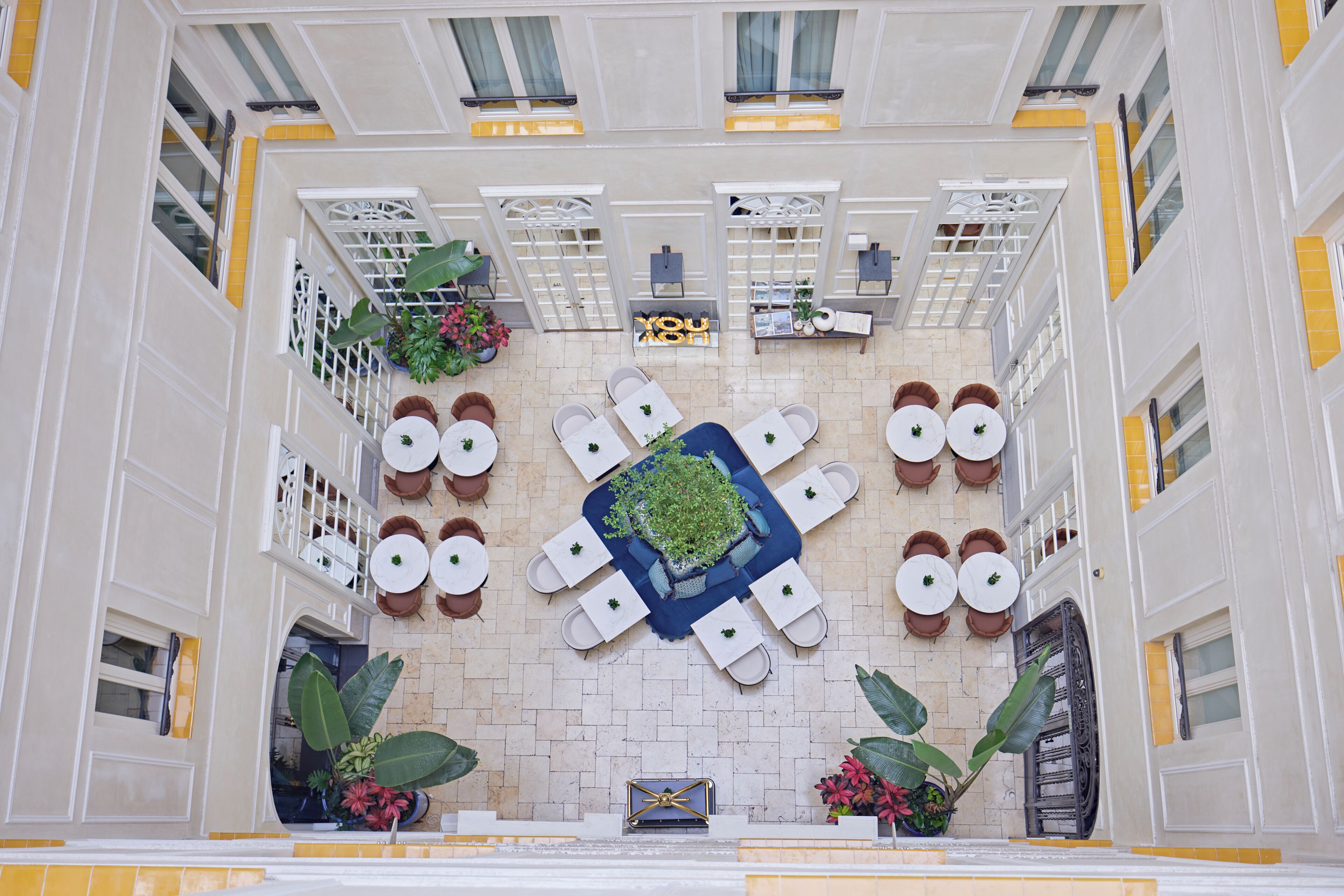 A hotel atrium with a central seating area, potted plants, and a decorative centerpiece.