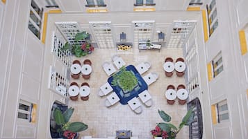 A hotel atrium with a central seating area, potted plants, and a decorative centerpiece.