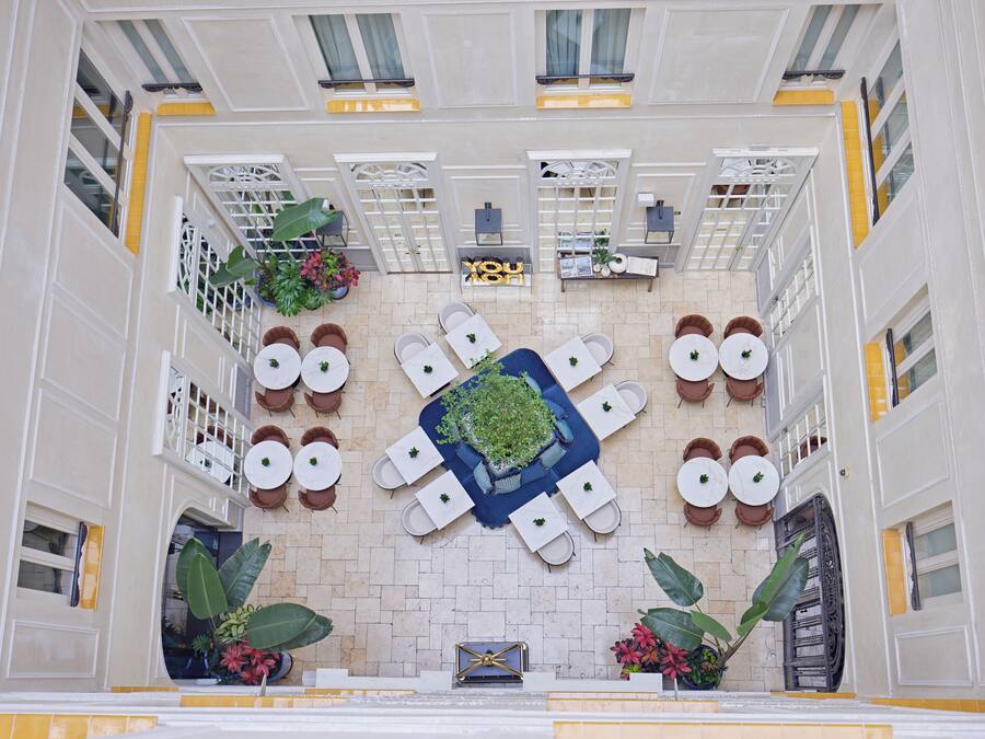A hotel atrium with a central seating area, potted plants, and a decorative centerpiece.