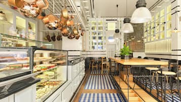 A modern kitchen with copper pots, a glass display case with food, and a blue and white checkered floor.