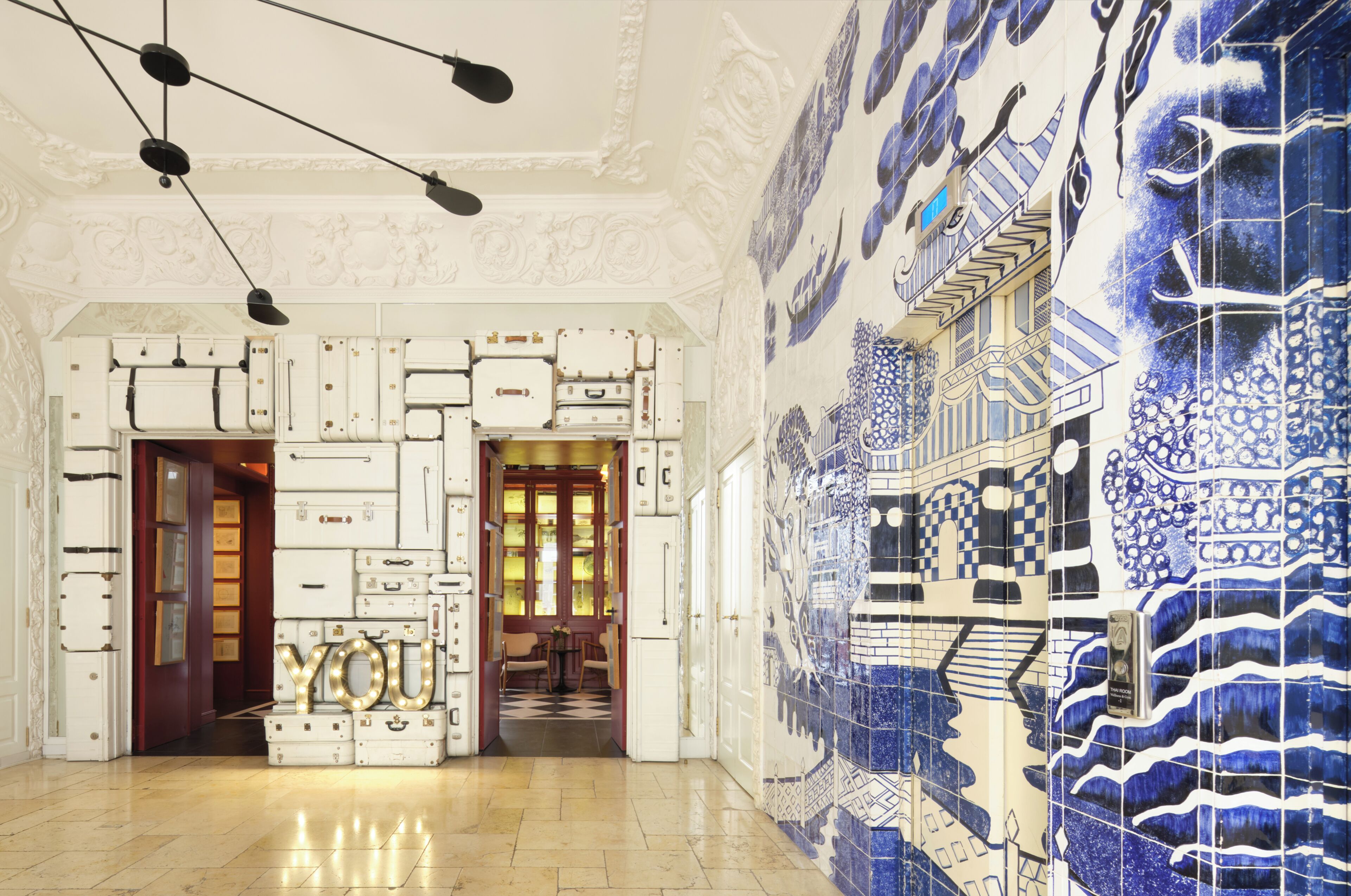 Un vestíbulo con pared de azulejos, una escalera y una puerta que da a una habitación.