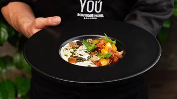 A person holding a black plate with a gourmet dish.