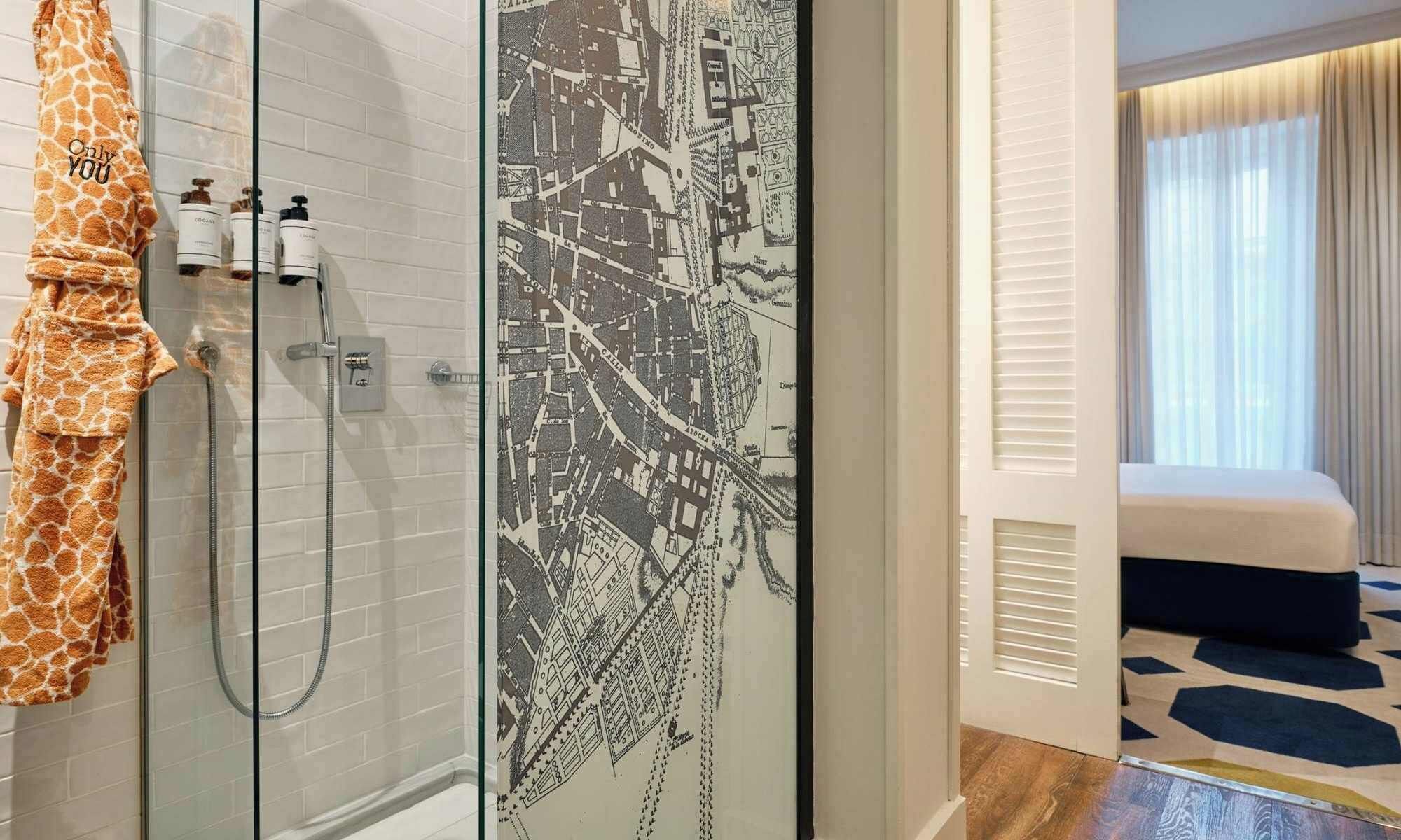 A modern bathroom with a shower, a towel rack with a towel, and a map on the wall.