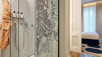 A modern bathroom with a shower, a towel rack with a towel, and a map on the wall.