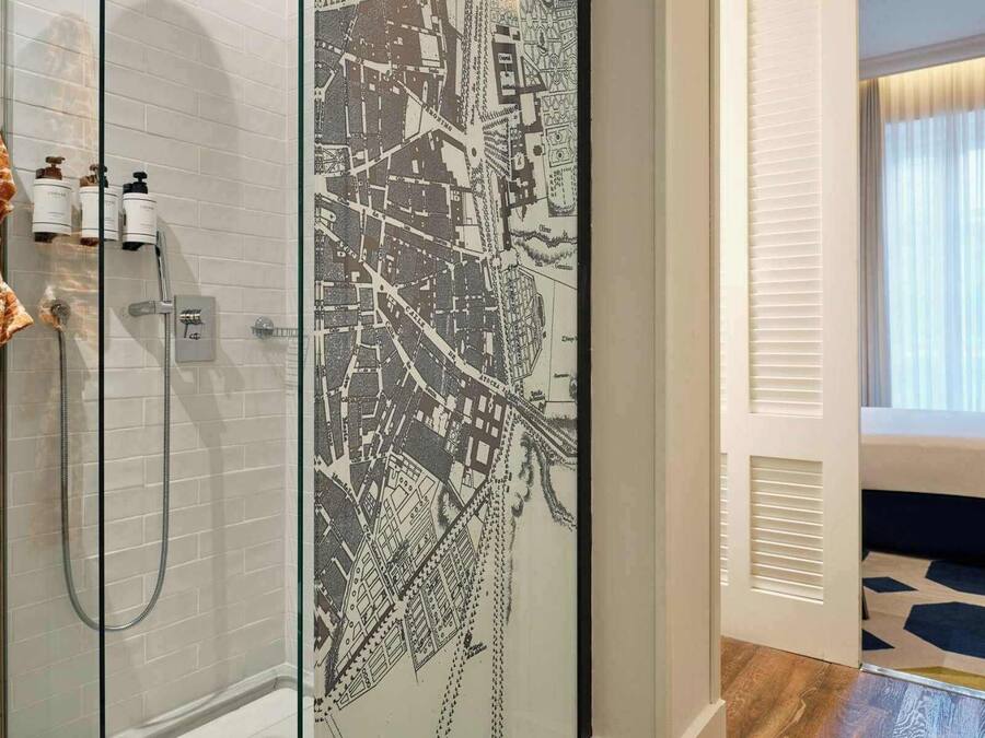 A modern bathroom with a shower, a towel rack with a towel, and a map on the wall.