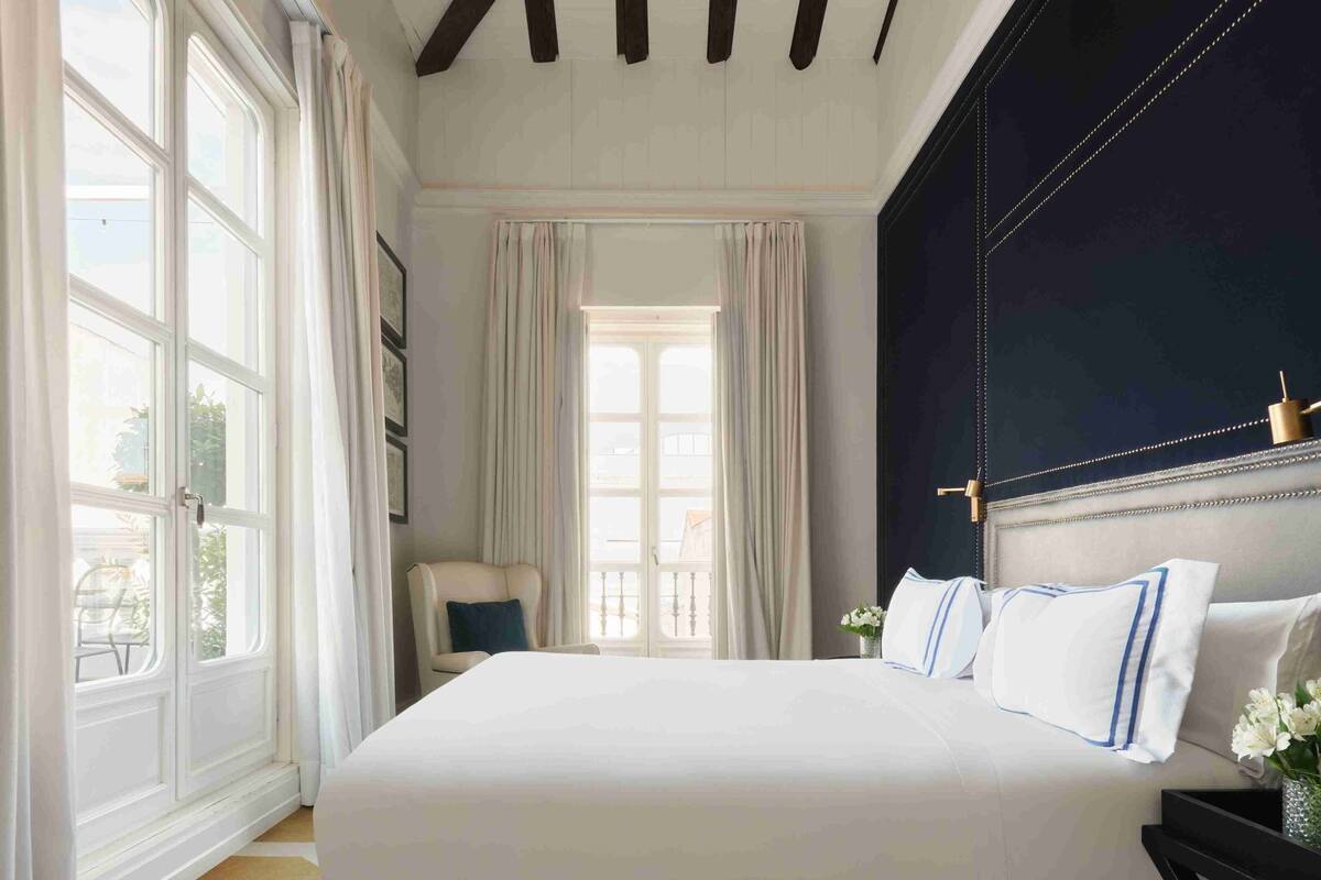 Une chambre avec un grand lit, un mur d’accent de couleur sombre et une vue par la fenêtre.
