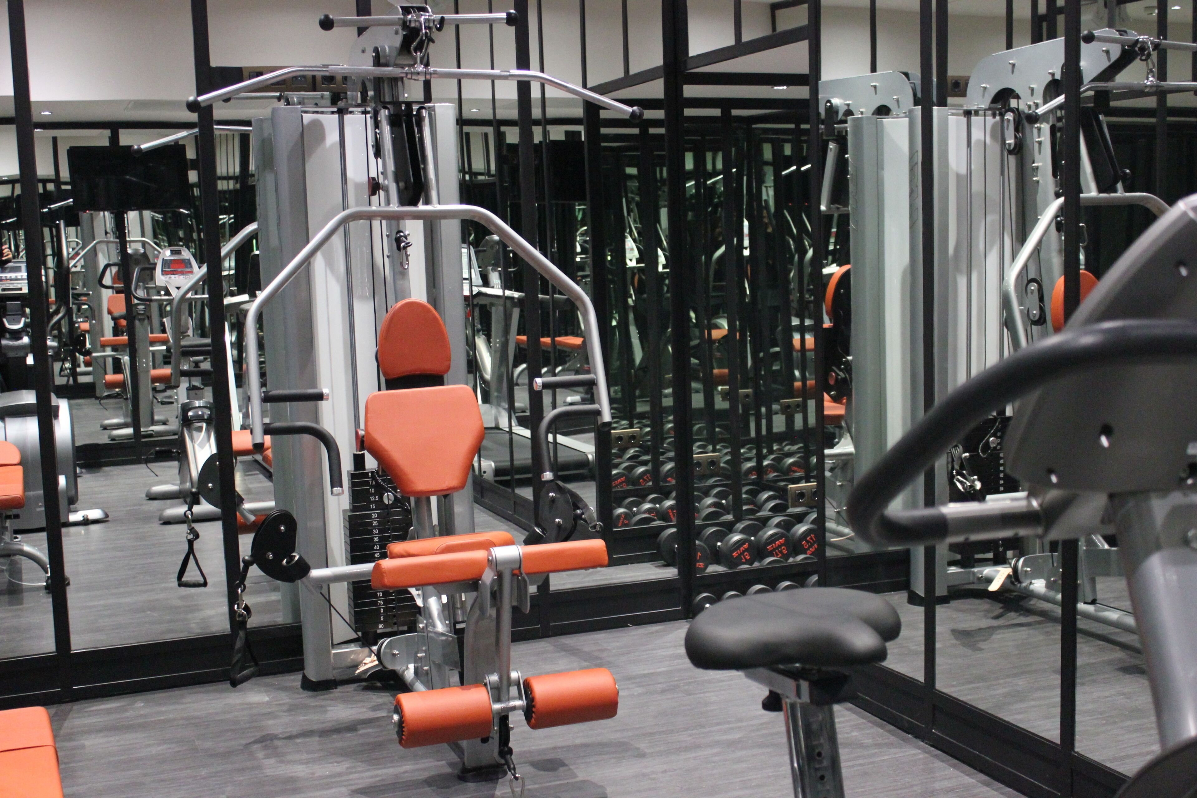 Un gimnasio con equipo de ejercicio, espejos y pesas.