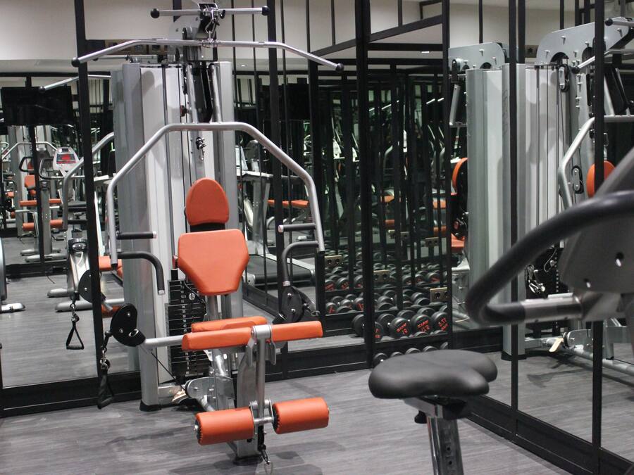 Un gimnasio con equipo de ejercicio, espejos y pesas.