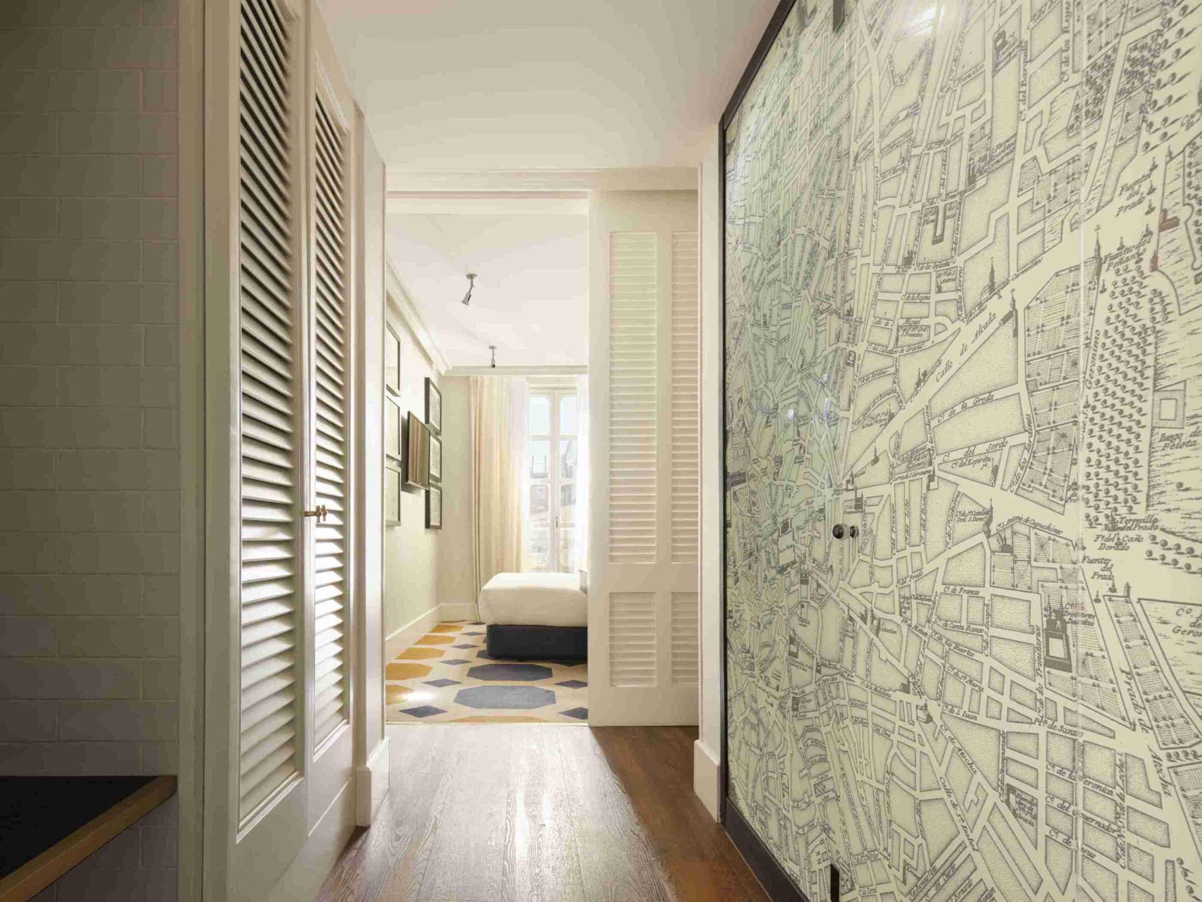 Un couloir avec un sol à motifs, un lit et une grande carte accrochée au mur.