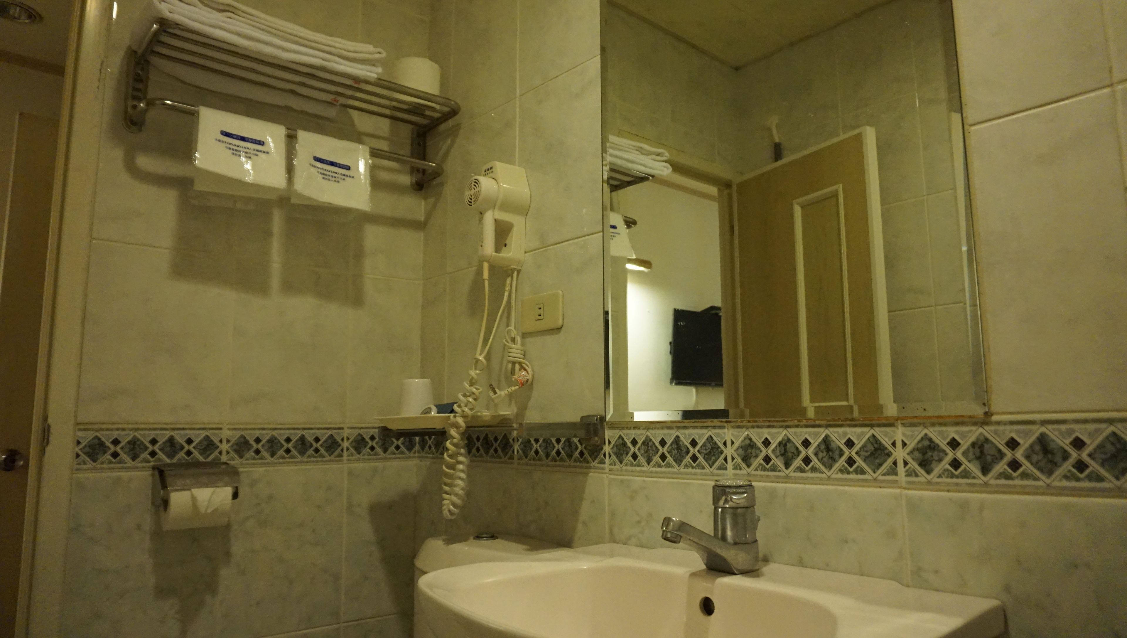 Un baño con lavamanos, espejo, toallero y artículos de aseo.