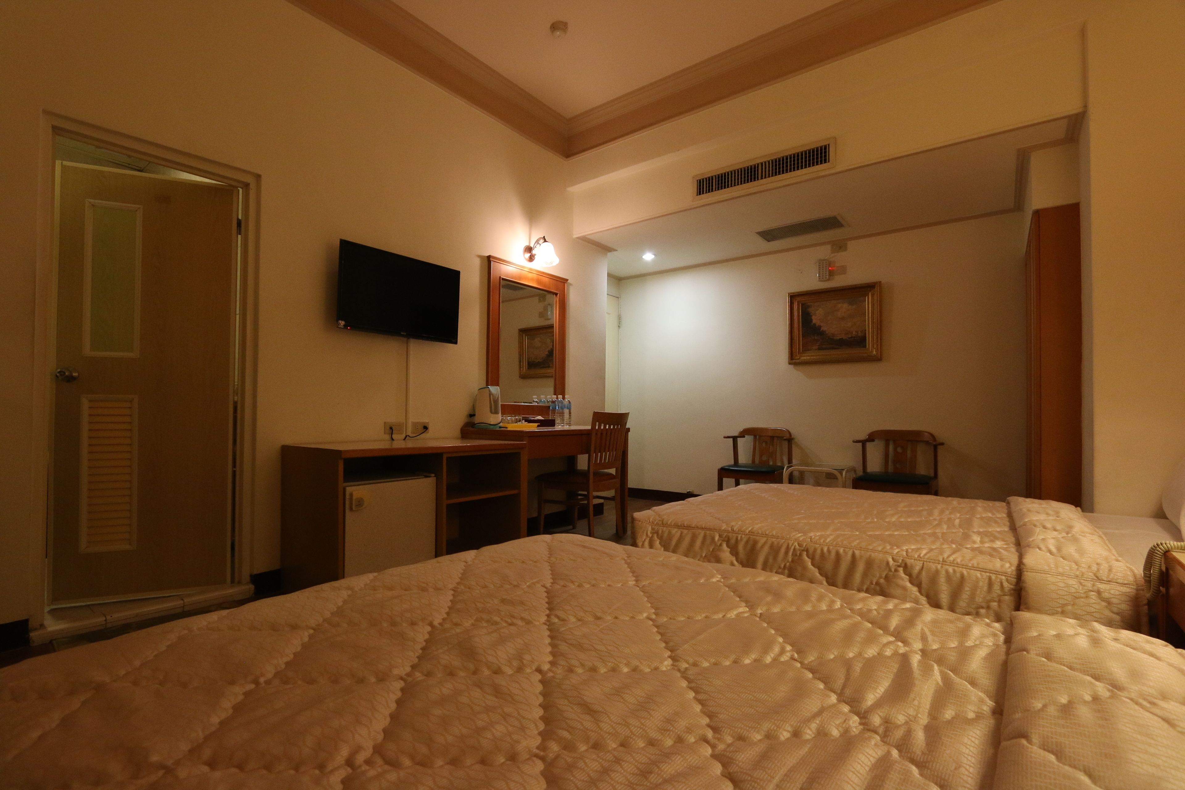 Une chambre d’hôtel avec deux lits, un bureau, une télévision et un miroir.
