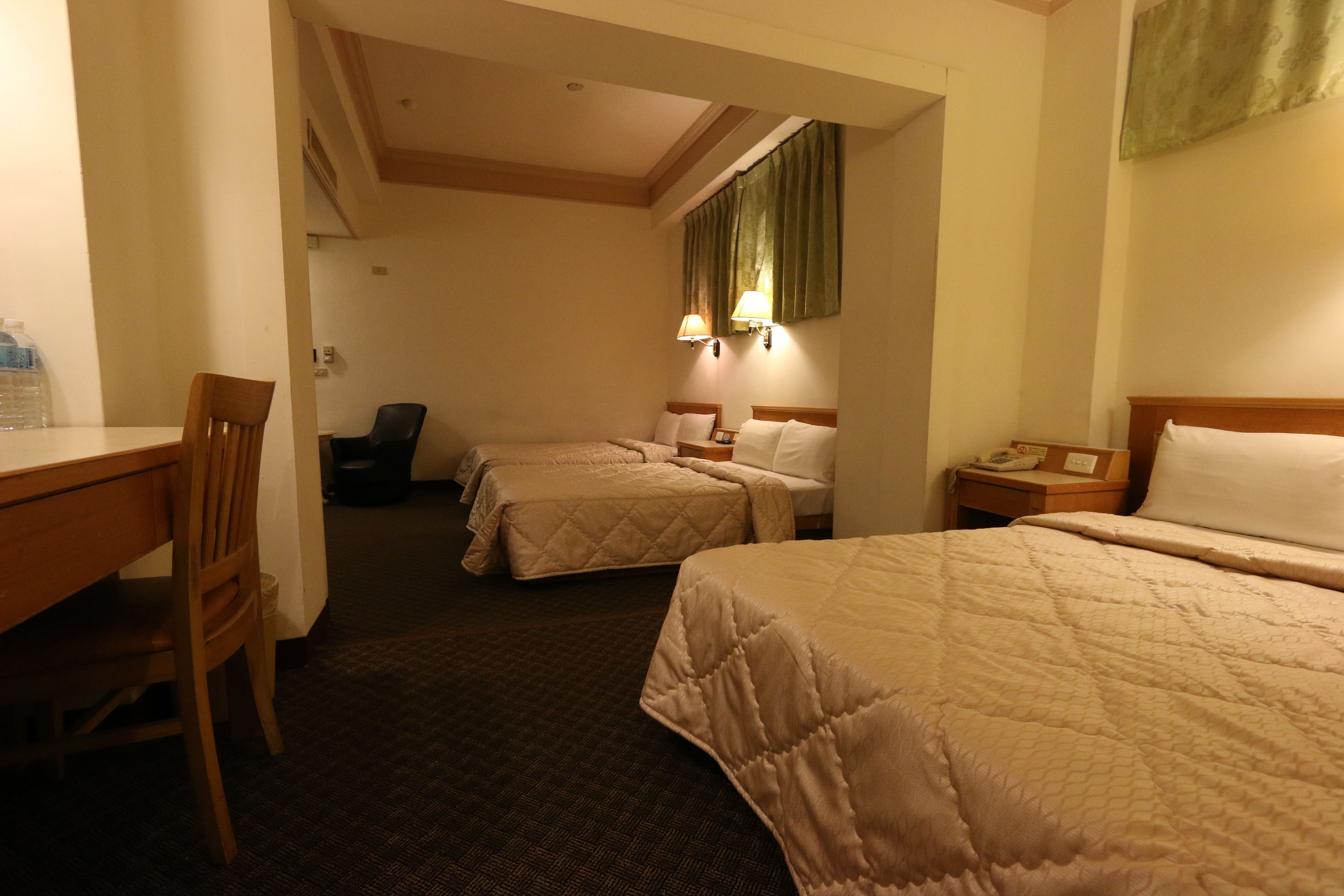 A hotel room with two beds, a desk, and a chair.