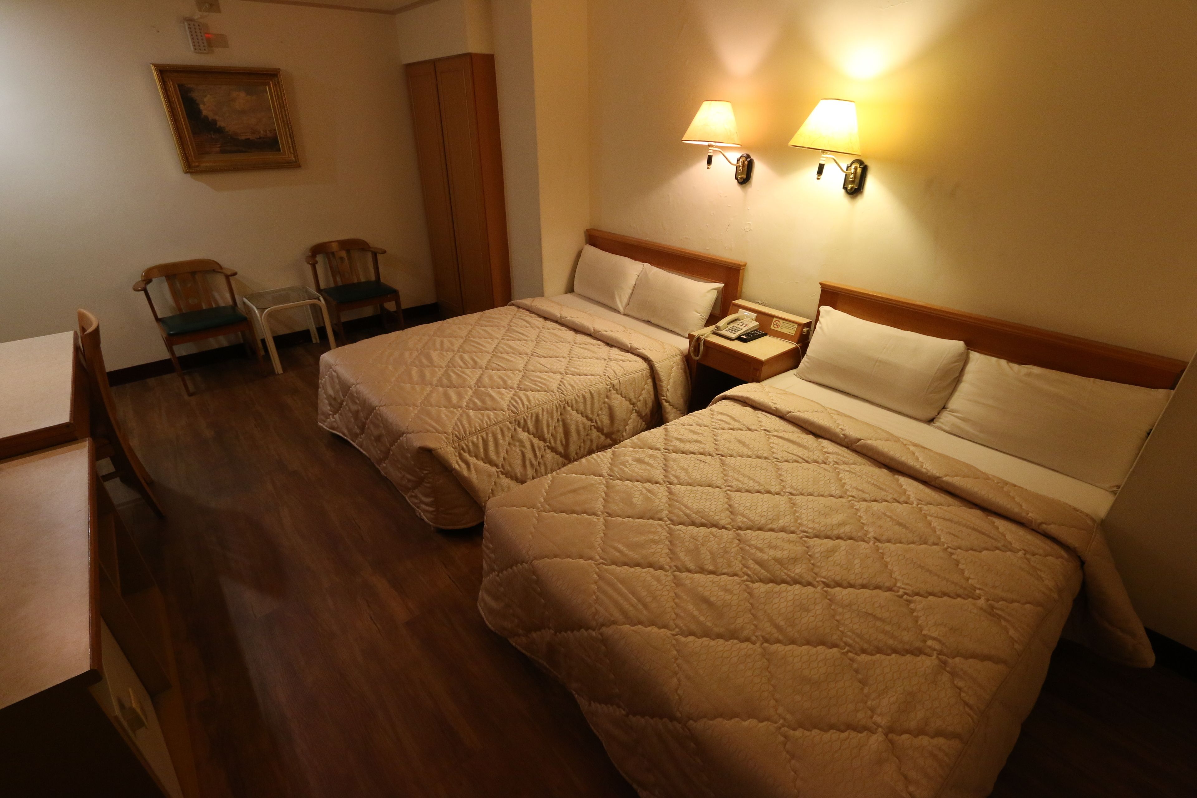 Een hotelkamer met twee bedden, een bureau, een stoel en een kledingkast.
