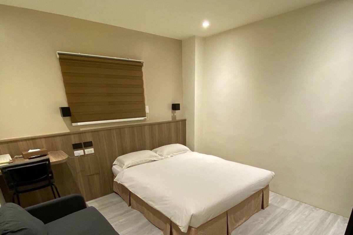 Ein modernes Hotelzimmer mit Bett, Schreibtisch und Stuhl.