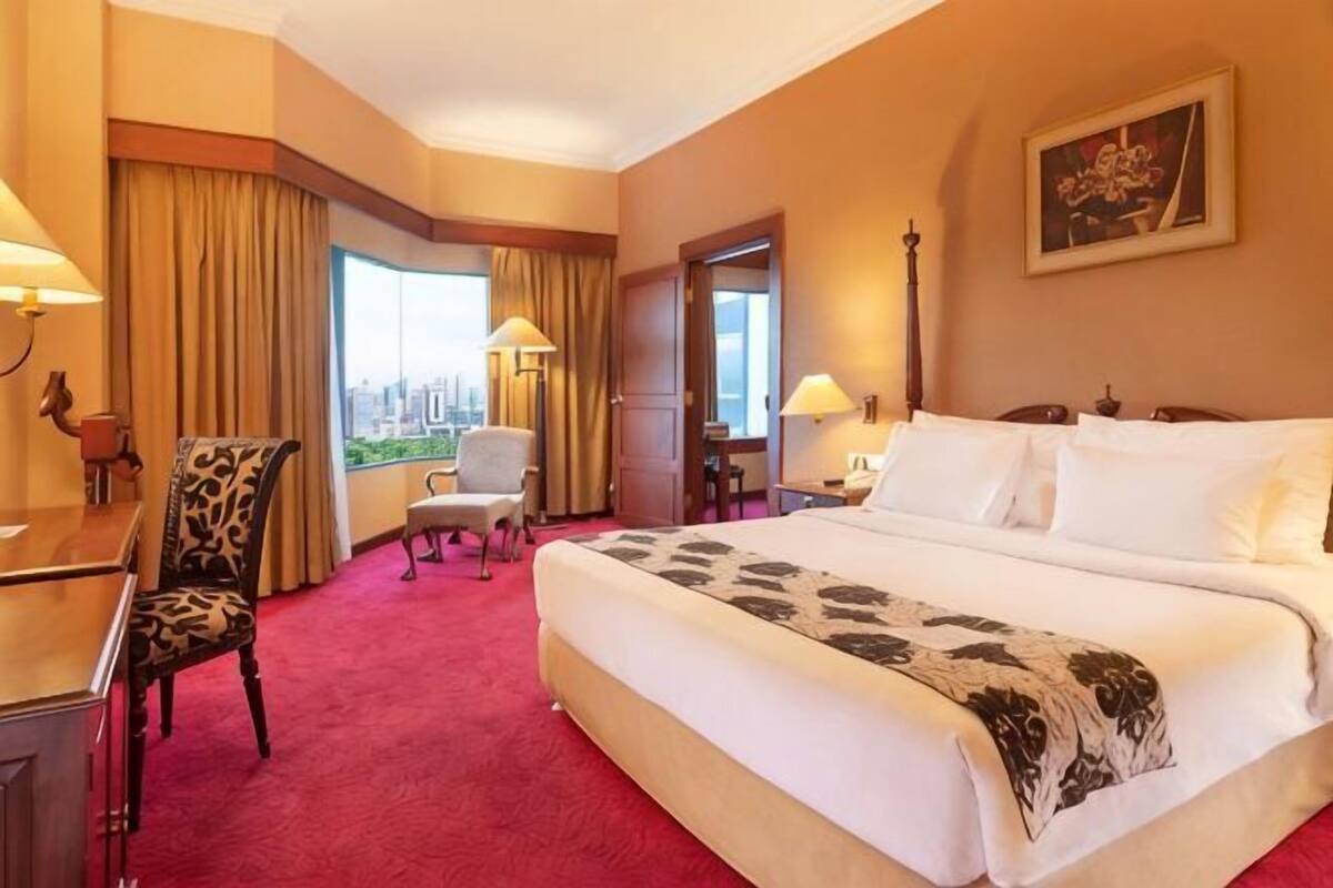Habitación de hotel con una cama grande, un escritorio, una silla y vistas a la ciudad.