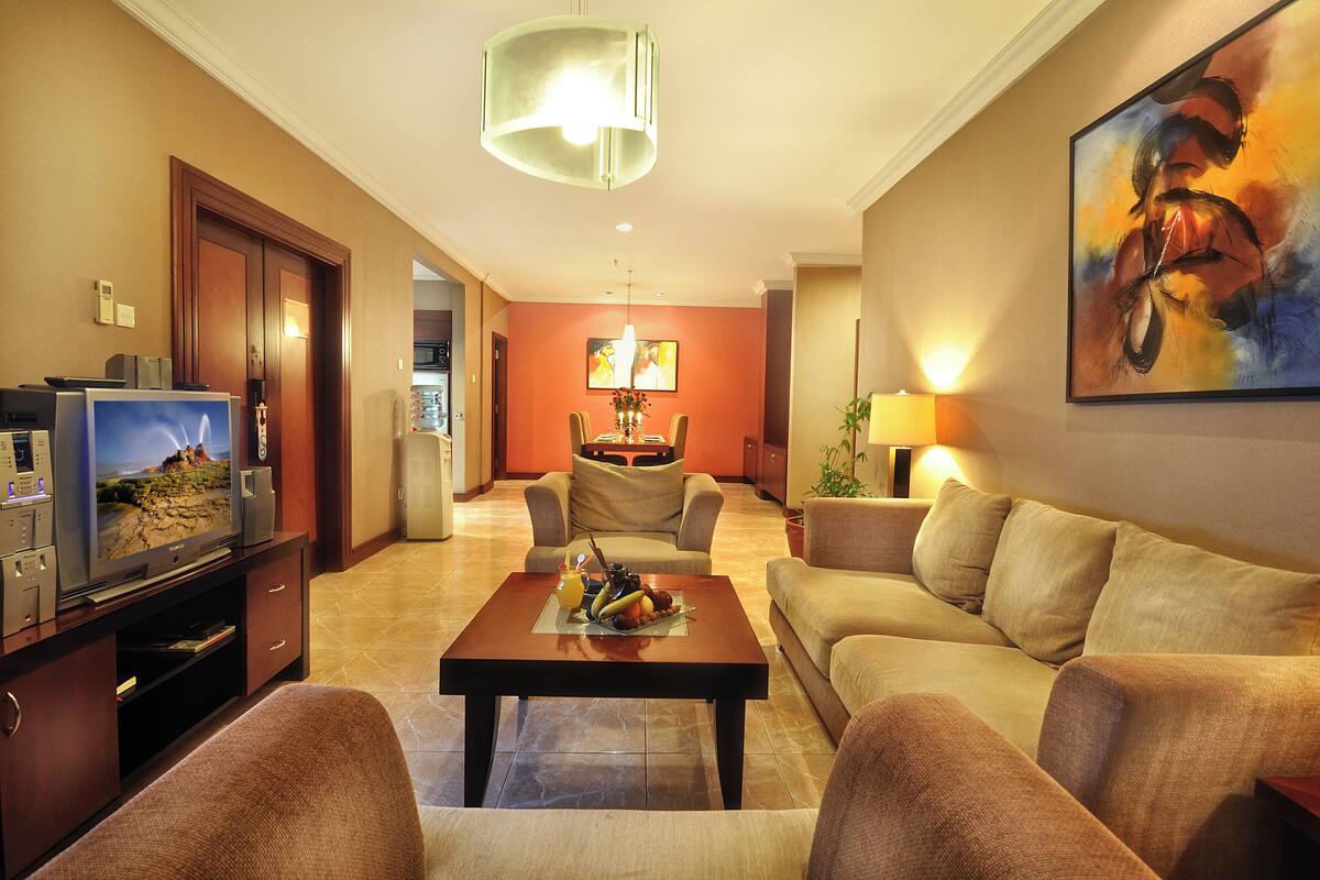 Una sala de estar con televisor, un comedor con mesa y sillas, y un sofá.